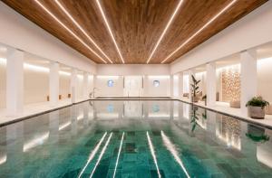 an indoor swimming pool with a wooden ceiling and a swimming poolinteger at Kimpton Aysla Mallorca by IHG in Santa Ponsa