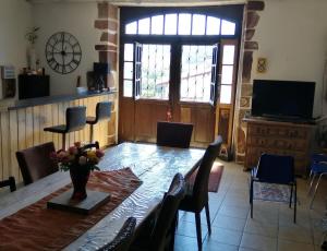 a dining room with a table and chairs and a television at Gîte Le Relais de la Source in Caro