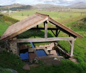 a dog house with a roof on top of a field at Gîte Le Relais de la Source in Caro