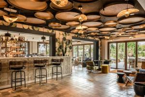 a restaurant with a bar with tables and chairs at Kimpton Aysla Mallorca by IHG in Santa Ponsa