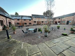 a courtyard with a table and chairs and brick buildings at King Charles Barns Nr Blists Hill in Telford