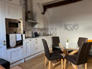 a kitchen with a glass table and black chairs at King Charles Barns Nr Blists Hill in Telford