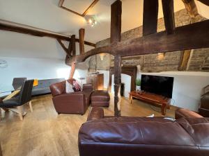 a living room with leather furniture and a stone wall at King Charles Barns Nr Blists Hill in Telford