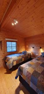 a bedroom with two beds in a log cabin at Fálki cottages in Þórshöfn