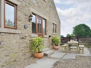 uma casa de pedra com uma mesa e dois vasos de plantas em The Old Dairy - Ukc3413 em Bolton by Bowland