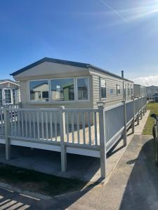 a mobile home with a porch and a fence at Palm grove in Chapel Saint Leonards