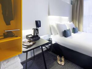 um quarto de hotel com uma cama e uma mesa com um telefone em ibis Styles Amsterdam Central Station em Amsterdã