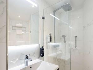 ein weißes Bad mit einem Waschbecken und einer Dusche in der Unterkunft ibis Styles Amsterdam Central Station in Amsterdam