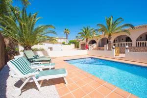 a pair of lounge chairs next to a swimming pool at Villa Capricho - PlusHolidays in Calpe