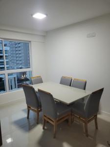 a table and chairs in a room with a window at Recanto Meia Praia in Itapema