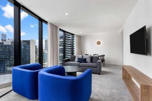 a living room with blue chairs and a tv at Adina Apartment Hotel Melbourne Southbank in Melbourne