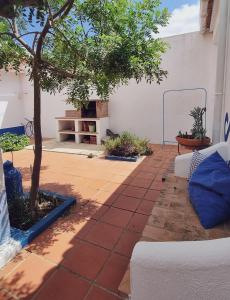 eine Terrasse mit einem Baum und einer weißen Wand in der Unterkunft Quintinha do Sal - Casa das Flores in Alcácer do Sal