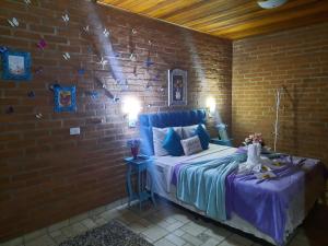 um quarto com uma cama numa parede de tijolos em Toca Hospedaria - Centro em São Bento do Sapucaí