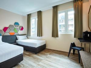 a hotel room with two beds and a chair at ibis budget Singapore Emerald in Singapore