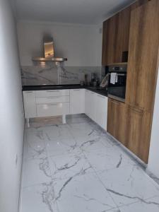 cocina con suelo de mármol y armarios de madera en 2 bedroom apartment in Bugibba, en St Paul's Bay