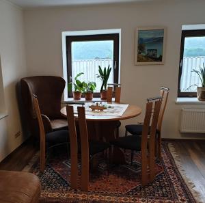 a dining room with a table and chairs and two windows at Ferienhaus Annemarie in Ludmannsdorf