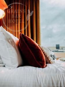 a bed with pillows on it with a window at Grains Bar Hotel in Oldham