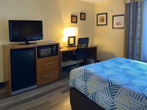 a hotel room with a bed and a desk with a television at Motel 6 Catonsville MD Baltimore West in Catonsville