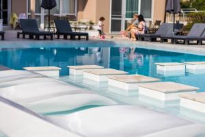 una piscina con gente sentada en sillas junto a ella en Selena Beach Family Hotel - All Inclusive Light en Sozopol