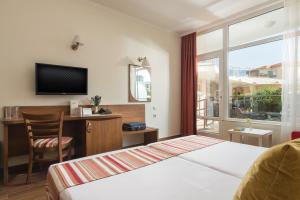 a hotel room with a bed and a desk and a window at Hotel Miramar Sozopol in Sozopol