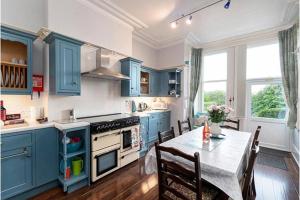 eine Küche mit blauen Schränken und einem Tisch mit Stühlen in der Unterkunft St Katherines in Llandudno
