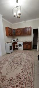 een keuken met houten kasten en een tapijt op de vloer bij Апартаменты на 14 этаже ЖК АРАЙ in Aqtöbe