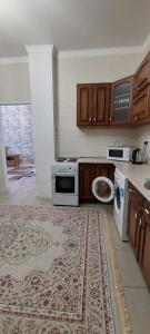 een keuken met een fornuis en een tapijt op de vloer bij Апартаменты на 14 этаже ЖК АРАЙ in Aqtöbe