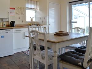 eine Küche mit einem Holztisch und Stühlen in der Unterkunft Merryview Bungalow in Orcop