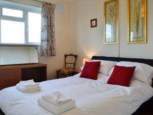 1 dormitorio con cama blanca y almohadas rojas en Merryview Bungalow, en Orcop