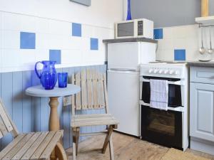 a kitchen with a table and a stove and a chair at South Cross Slacks Farmhouse in Crovie
