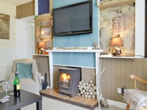 a living room with a fireplace and a tv at South Cross Slacks Farmhouse in Crovie