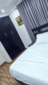 a bedroom with a white bed with a black headboard at Naboya House Serviced Apartment in Benin City