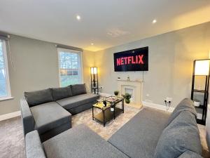 uma sala de estar com um sofá e uma televisão na parede em Luxurious Harrogate Penthouse with Free Parking em Harrogate