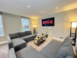a living room with a couch and a television on the wall at Luxurious Harrogate Penthouse with Free Parking in Harrogate