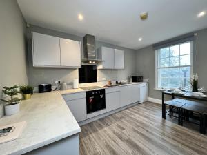 uma grande cozinha com armários brancos e uma mesa em Luxurious Harrogate Penthouse with Free Parking em Harrogate