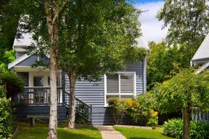 ein graues Haus mit einer Veranda und Bäumen in der Unterkunft Lake Orchard Villas in Daylesford