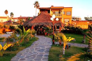 a house with a straw umbrella and a walkway at 5 bedroom Beachfront pool & Spa in Ensenada