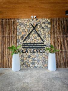 two white vases with plants in front of a wall at La Levée Resort in Sai Yok