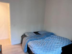 Schlafzimmer mit einem Bett mit blauer Decke in der Unterkunft Elegance et Confort - Votre Havre Luxueux pour les Jeux Olympiques à Paris in Puteaux
