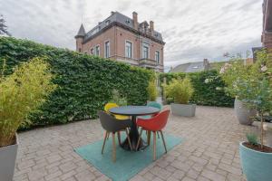 un patio con mesa y sillas frente a un edificio en Superbe appartement 2 chambres dans un clos privé proche de Waterloo, en Genappe