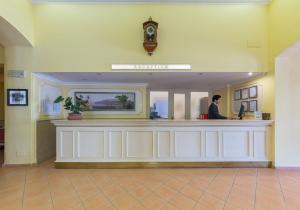 a man standing at a reception counter in a lobby at Hotel Jaccarino in SantʼAgata sui Due Golfi