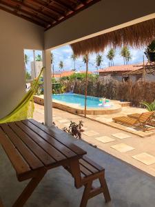eine Terrasse mit einer Holzbank und einem Pool in der Unterkunft Pousada Vila Lua Bela in Pitimbu