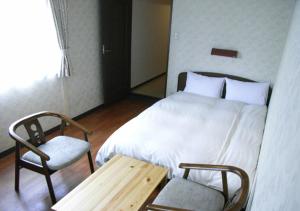 a bedroom with a bed and a table and a chair at Sunplaza Rinkai in Osaka