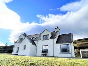 a white house on the side of a hill at Tigh Fraoich in Carbost