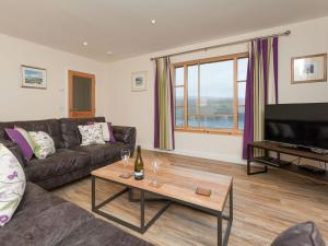 a living room with a couch and a flat screen tv at Tigh Fraoich in Carbost