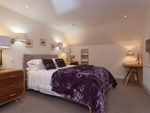 a bedroom with a large bed with a purple blanket at Tigh Fraoich in Carbost