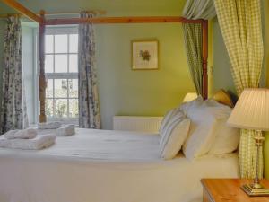 a bedroom with a large white bed with a window at Osprey Cottage - Uzq in Kirkton of Airlie