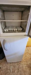 einen weißen Kühlschrank mit offener Tür in einem Zimmer in der Unterkunft Cabaña Don Justino in El Calafate