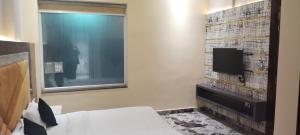 a hotel room with a bed and a tv at Hotel K J International in Pura Raghunāth