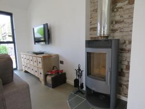 a living room with a fireplace and a television at Umber, Gallery Cottages, Devon in West Putford